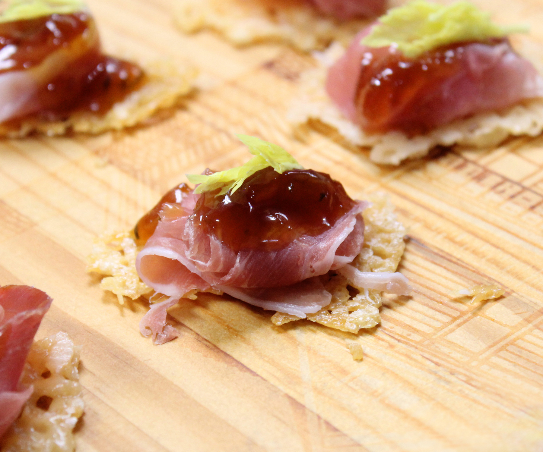 Parmesan crisps with Prosciutto and orange marmalade preserves topped with fresh celery leaves