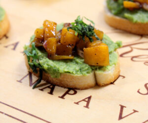 Crostini topped with arugula hummus and butternut squash relish, fresh basil and balsamic vinegar